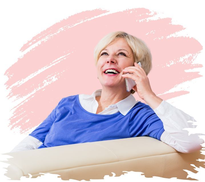 Photo of a woman sitting on a couch while smiling on the phone. Background is white with a large pink paint stroke.