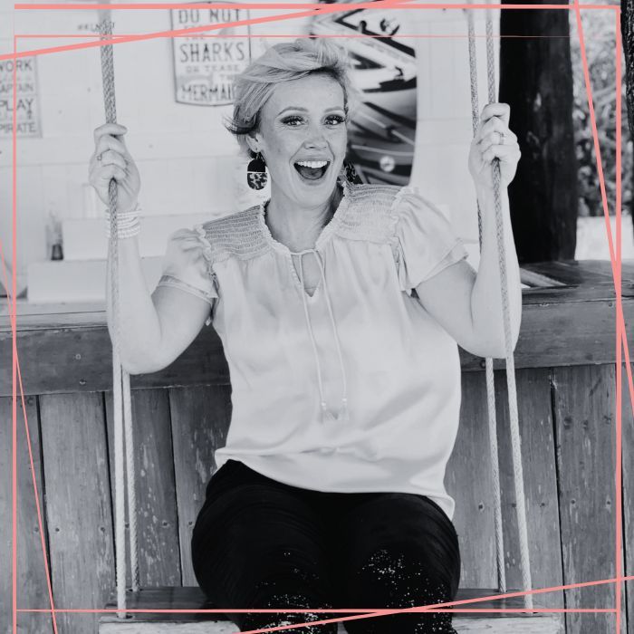 Black and white photo of Jordana G smiling while on a swing. Around the image are pink lines bordering the square image.